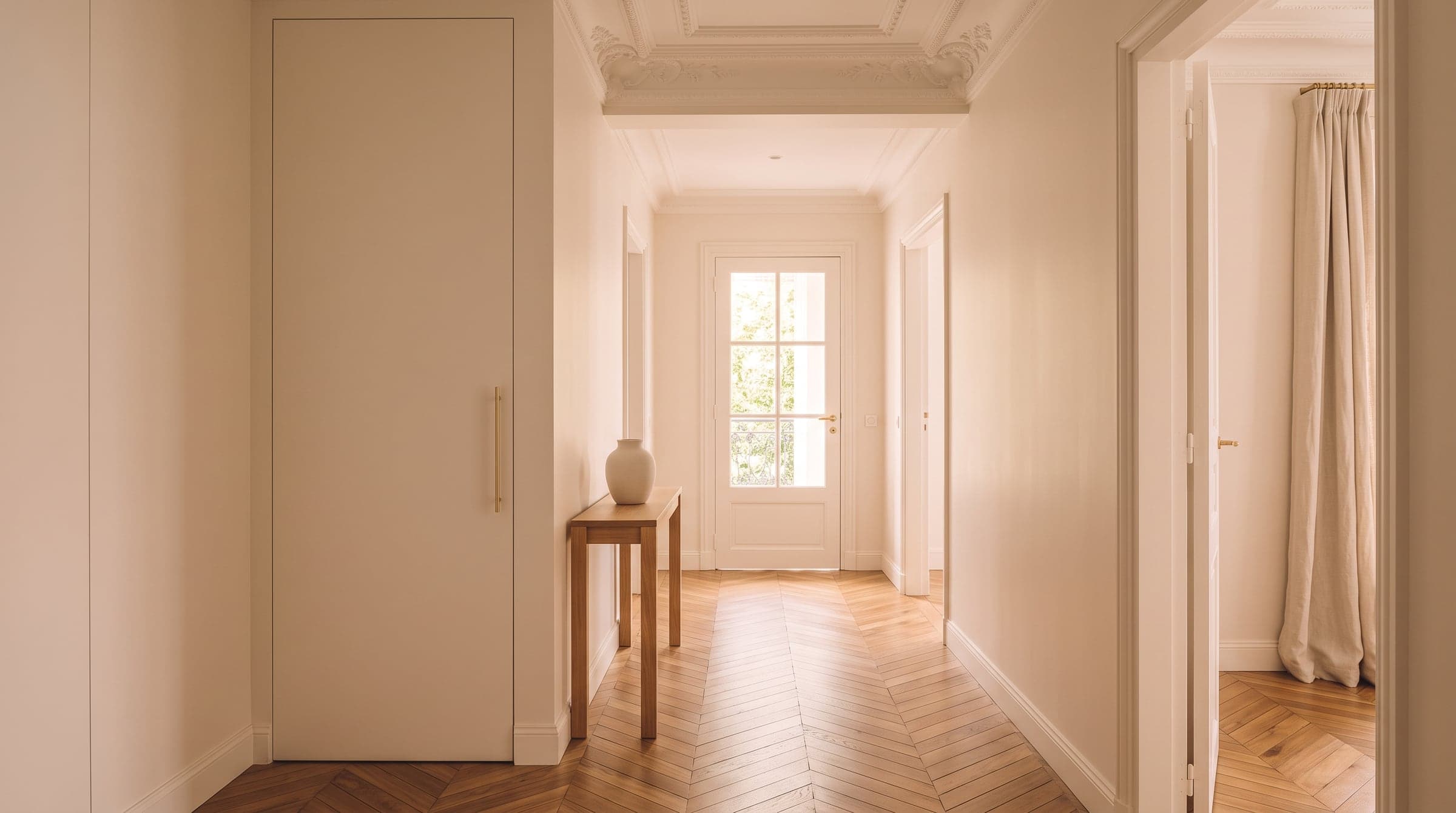 Placard fermé dans une entrée haussmannienne, porte menuisée dans la teinte des murs, aucune trace de la buanderie derrière
