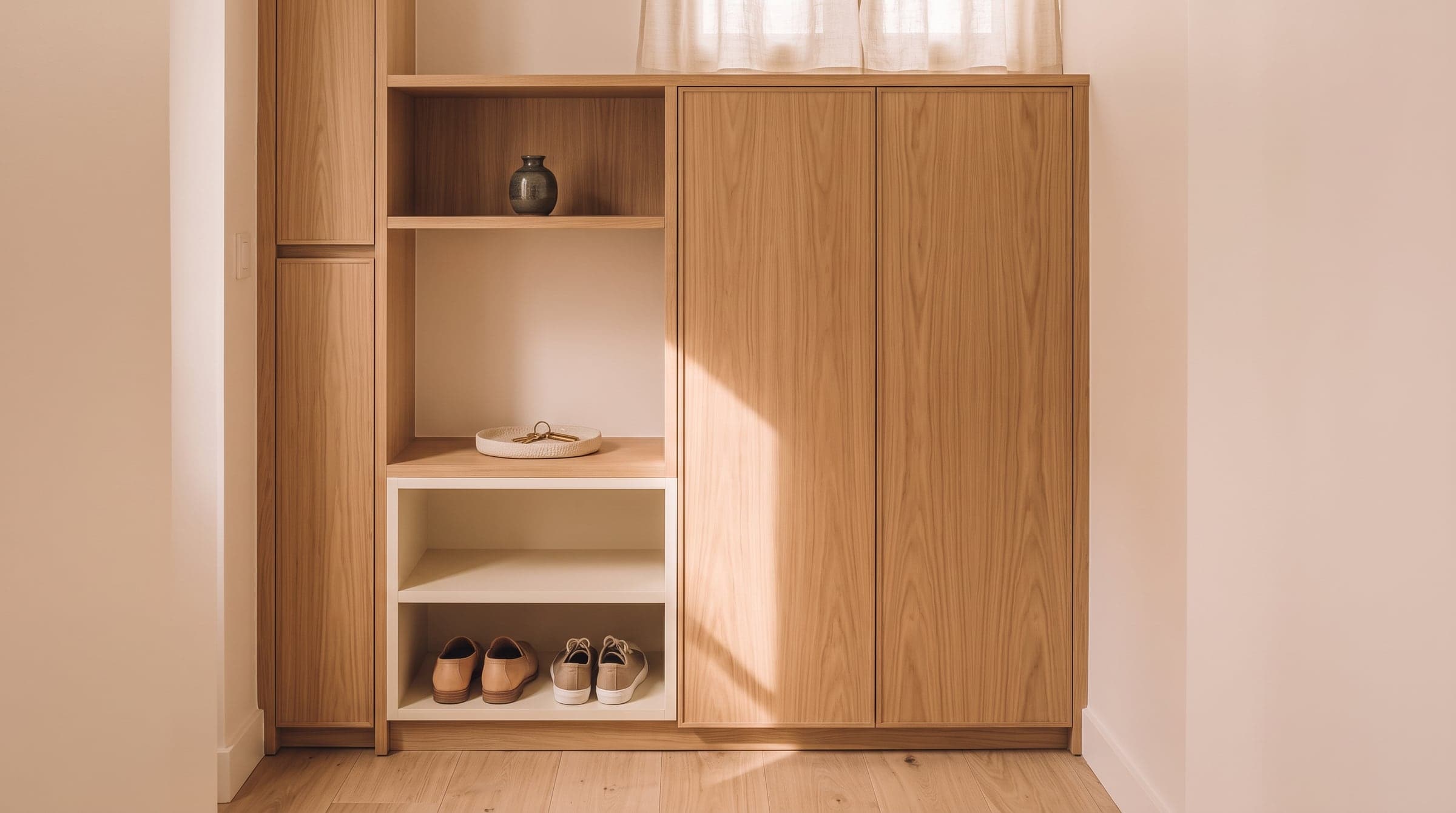 Built-in oak hallway storage with a closed coat cupboard beside an open shelf for shoes and keys