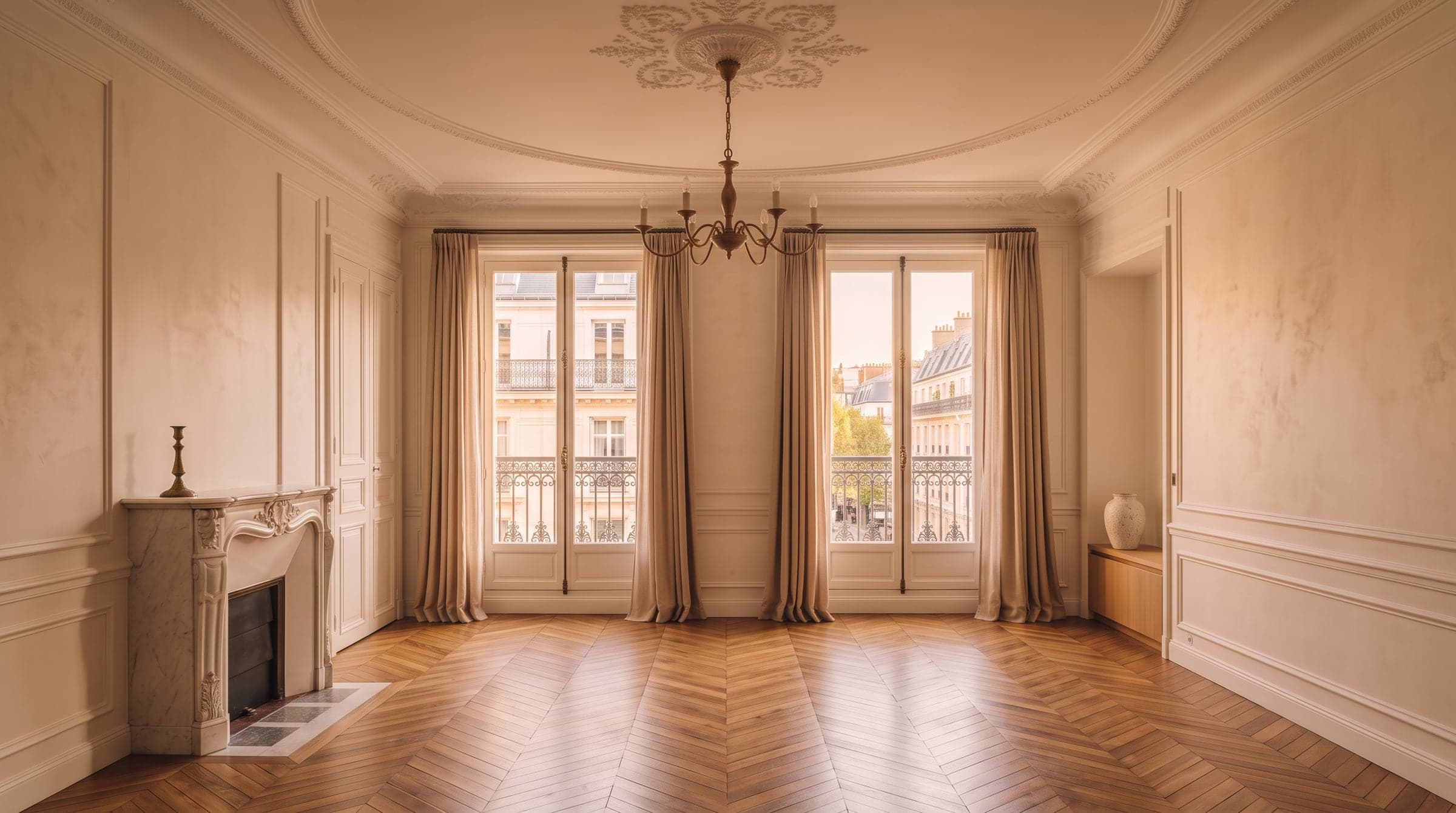 A bright, high-ceilinged Paris room with herringbone parquet and ceiling mouldings, sunlight falling across the floor