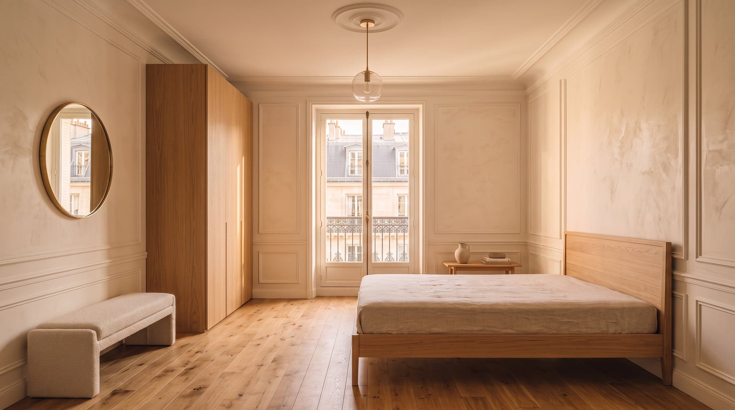Oak furniture being installed in an empty Paris apartment room with a tall window and zinc rooftops outside