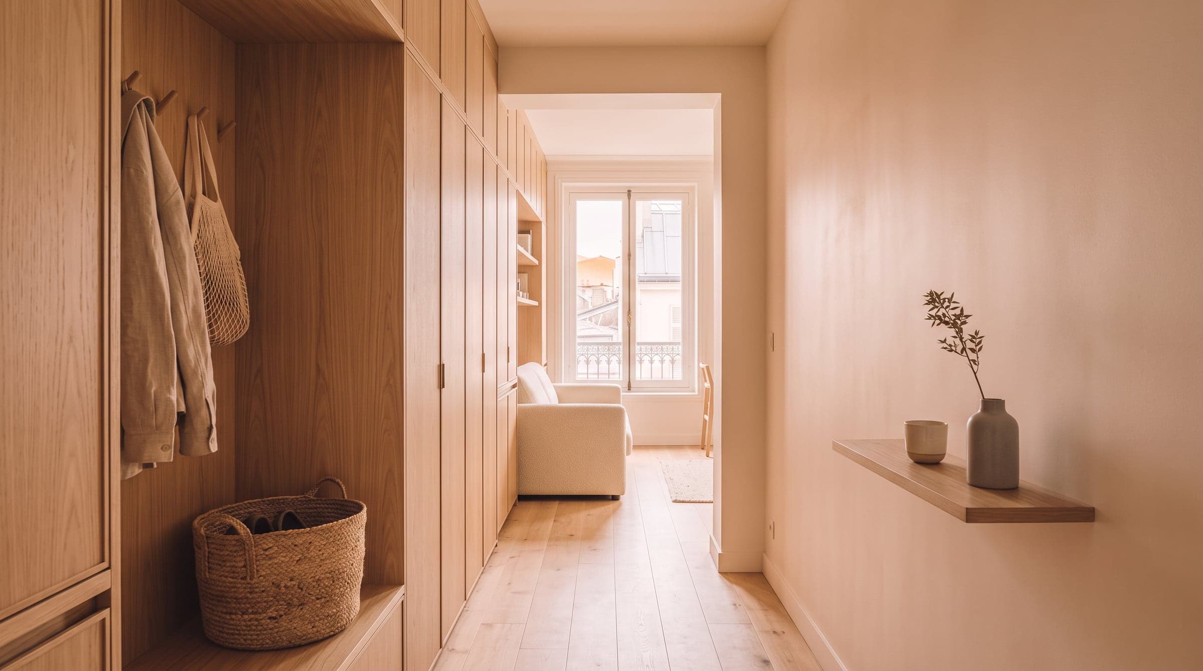 Narrow entrance corridor lined with full-height oak cupboards and coat hooks, daylight spilling in from an open door at the far end