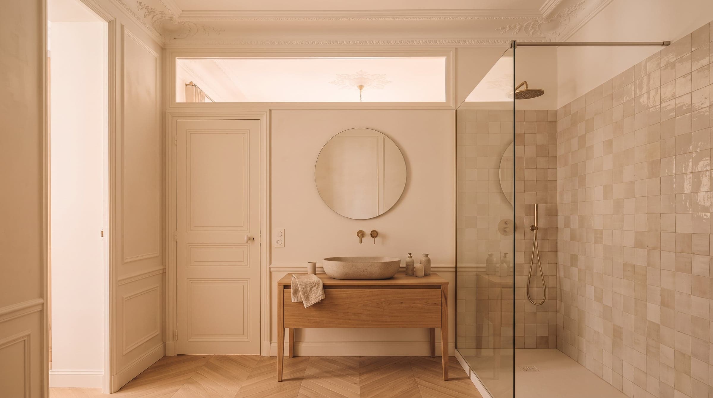 Petite salle d'eau avec douche à l'italienne, vasque en pierre et panneau de verre dépoli au-dessus de la porte laissant passer la lumière du dressing