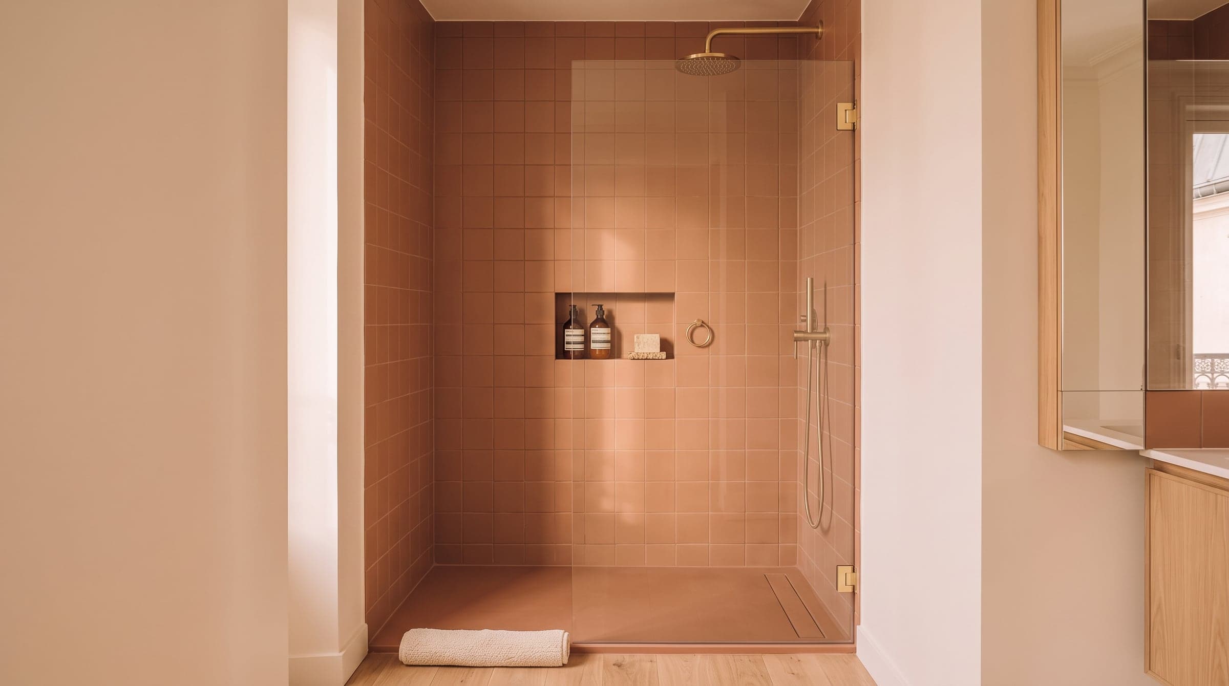 Narrow walk-in shower with a glass screen and a recessed shelf built into the tiled wall