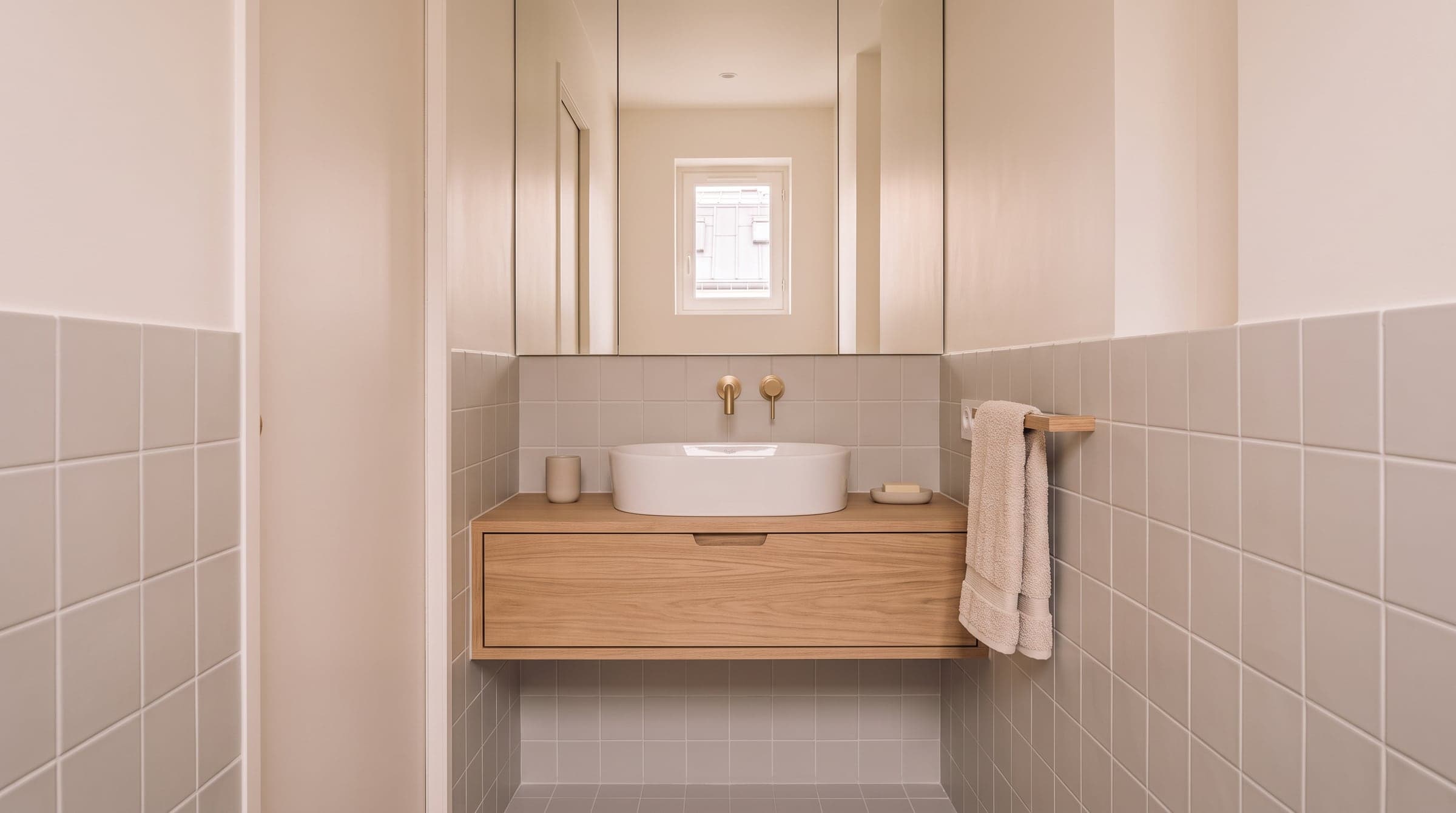 Wall-hung basin under a wall-to-wall mirror with an oak vanity cabinet fixed below it